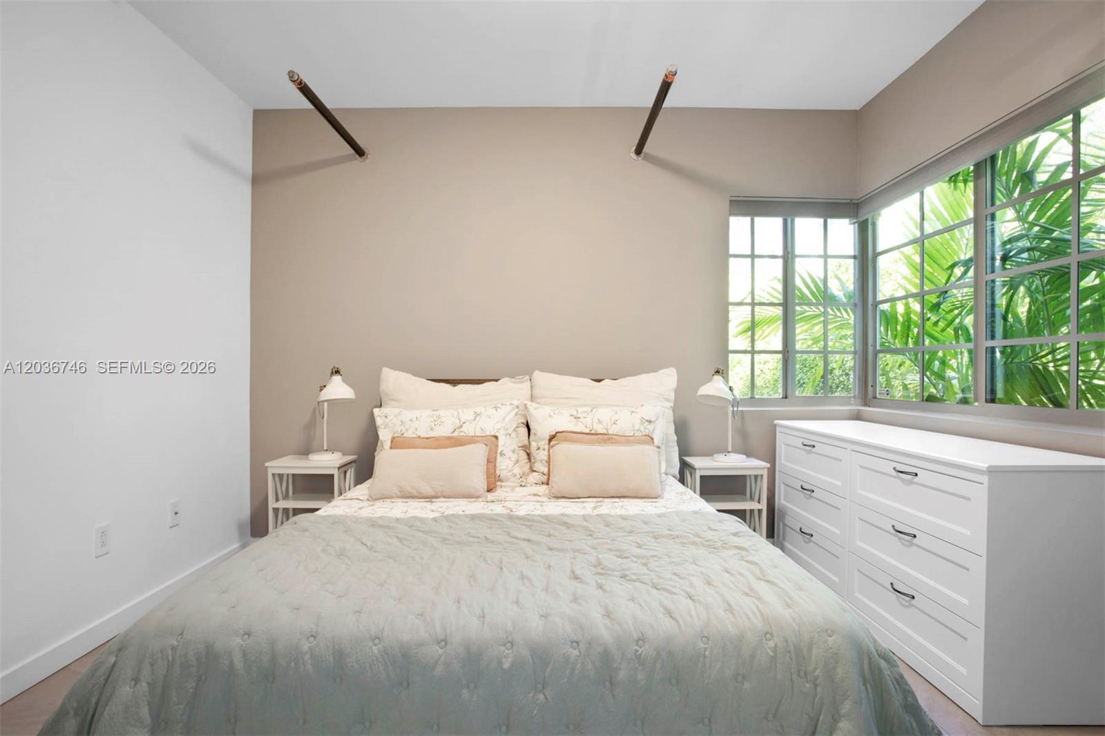 A bedroom features a bed with a light blue quilt, white nightstands, and corner windows — 901 3rd St # 3, Miami Beach FL 33139, MIAMI BEACH, FL