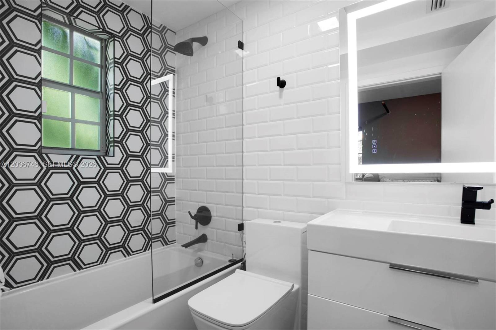 A modern bathroom features a white subway tile shower, geometric patterned walls, and a vanity — 901 3rd St # 3, Miami Beach FL 33139, MIAMI BEACH, FL