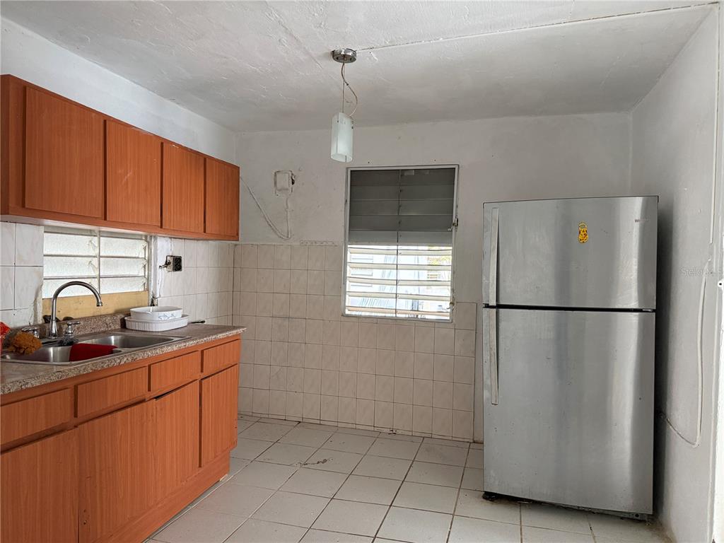A kitchen features wood cabinets, a stainless steel refrigerator, tiled walls, and a tiled floor — Carr. 901 CAMINO NUEVO, YABUCOA, PR