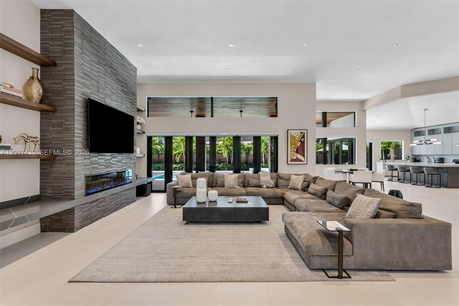 A modern living room features a large sectional sofa, stone fireplace, and open-concept kitchen — 10040 SW 124th St, Miami FL 33176, MIAMI, FL