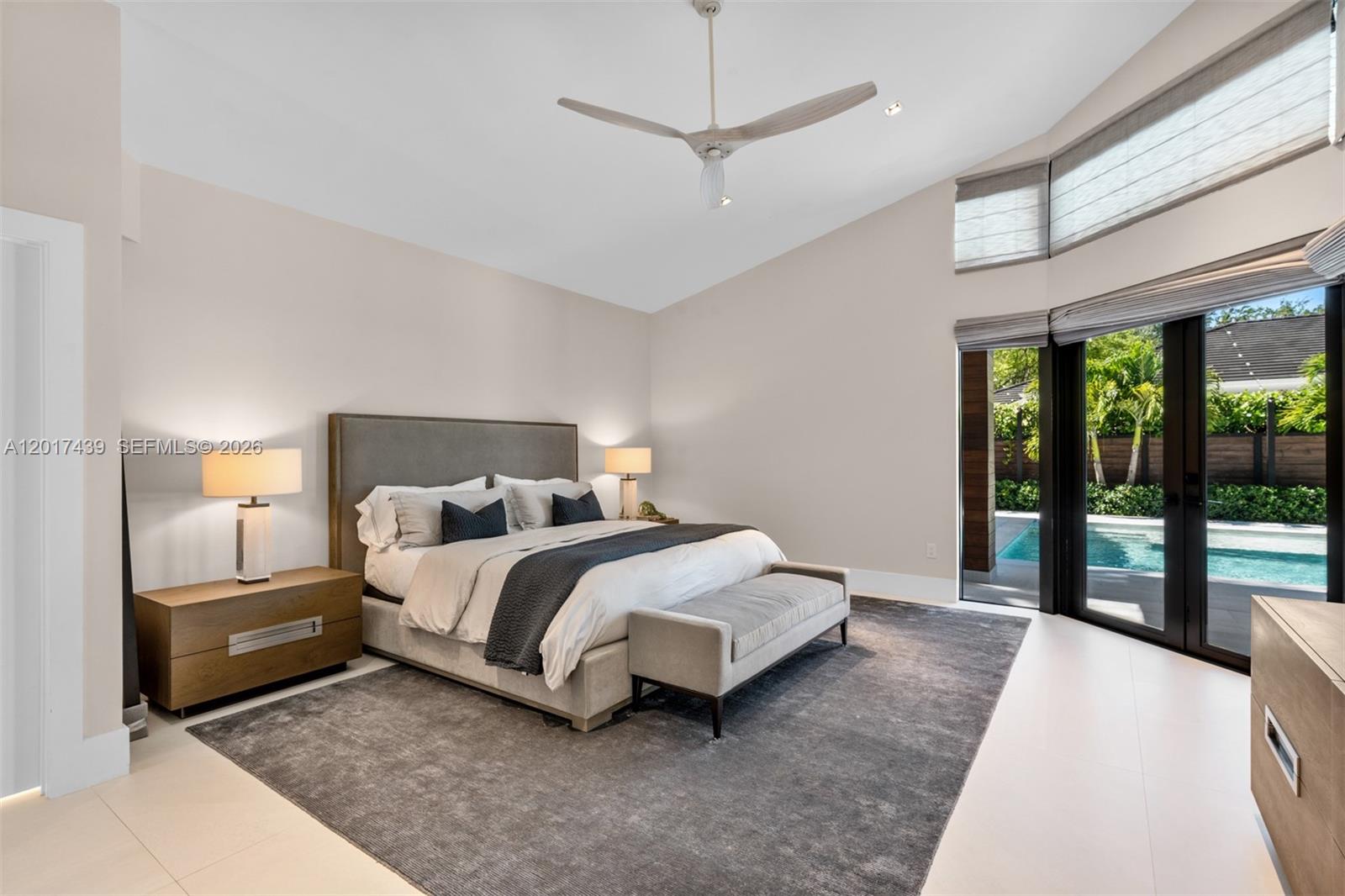 A modern bedroom features a king bed, gray area rug, and sliding doors to a pool — 10040 SW 124th St, Miami FL 33176, MIAMI, FL