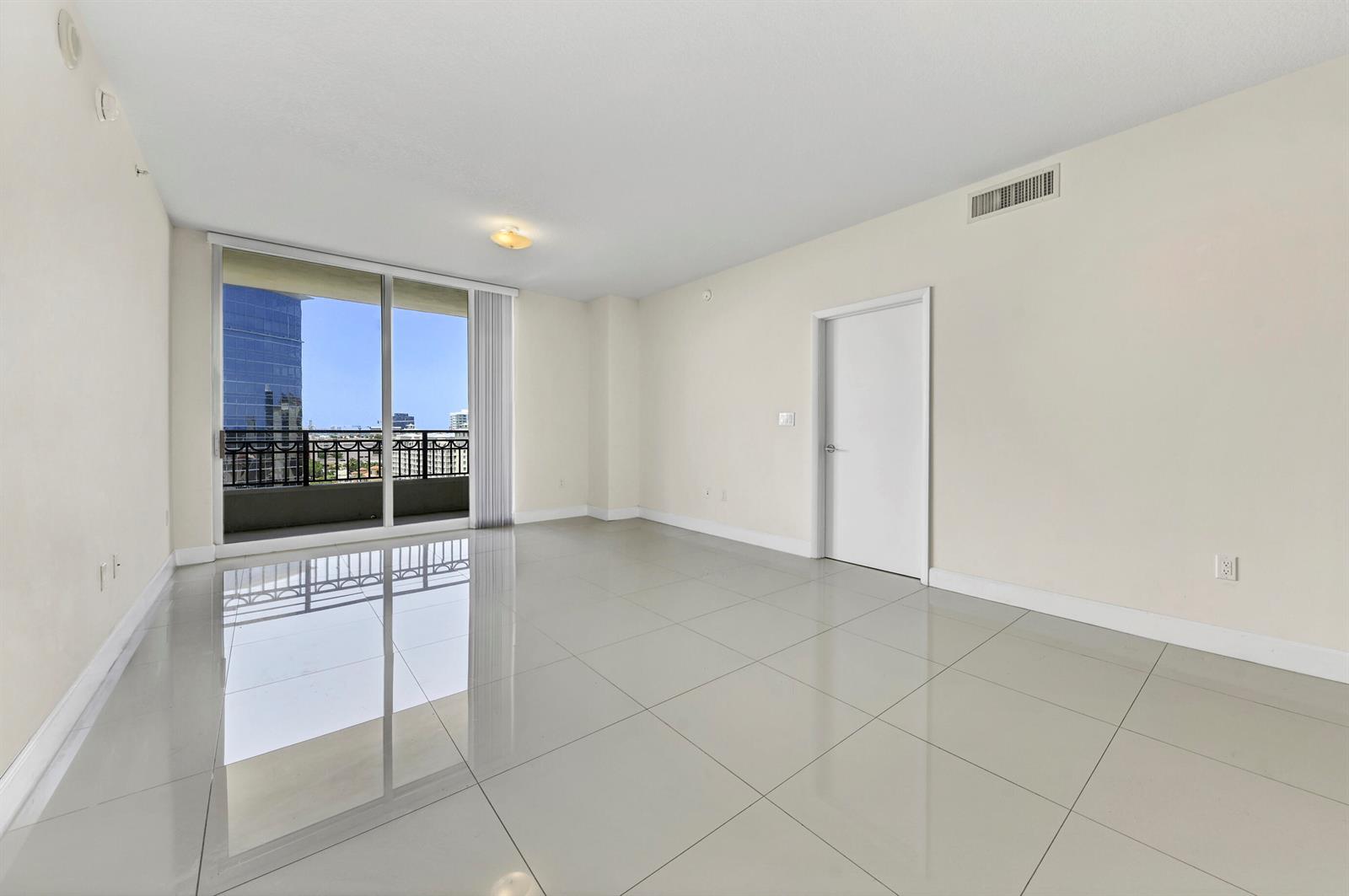 An empty room with large light-colored floor tiles, a white door, and a balcony view — 550 Okeechobee Boulevard # 1404, West Palm Beach FL 33401, WEST PALM BEACH, FL