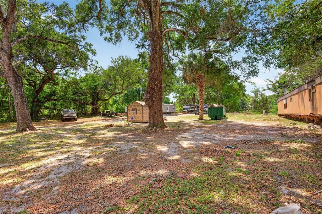 A large, wooded lot features a small shed, a dumpster, and a mobile home — 17684 NE 24TH AVENUE, CITRA, FL