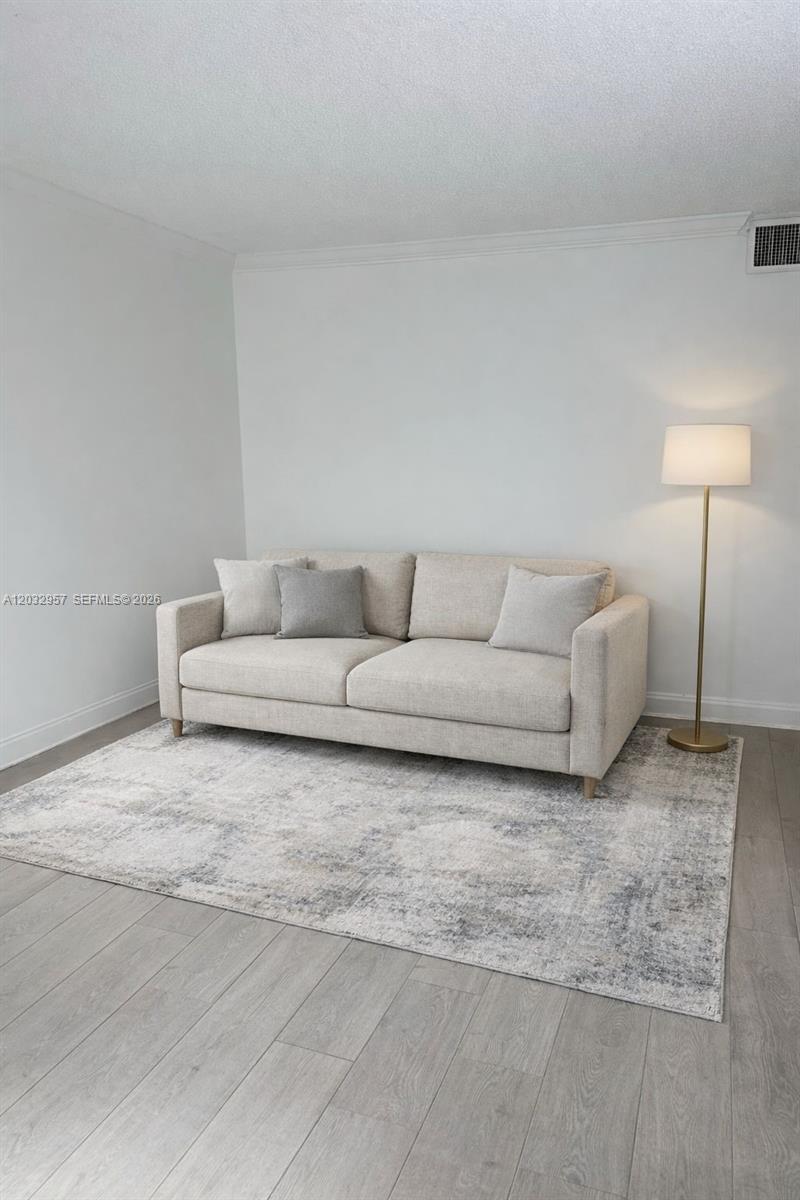 A beige sofa sits on a patterned area rug in a room with light flooring — 2008 N Jackson St # B4, Hollywood FL 33020, HOLLYWOOD, FL