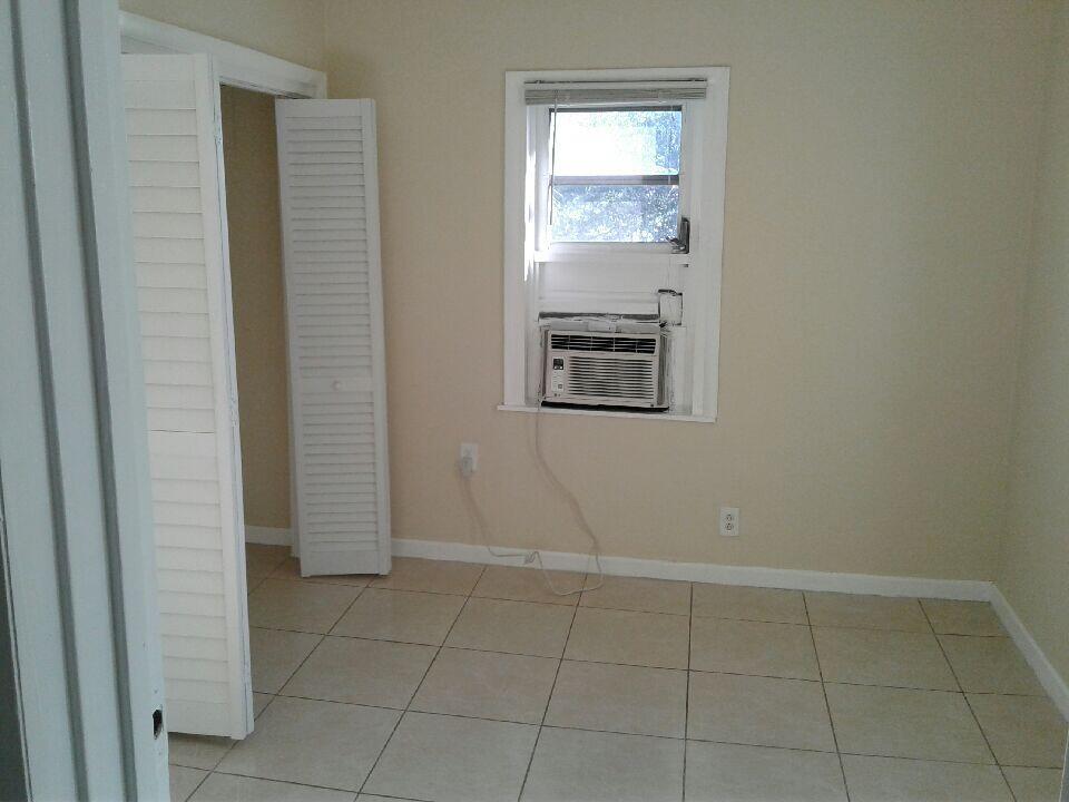 An empty room with beige walls, tile flooring, a window air conditioner, and a closet — HOLLYWOOD, FL