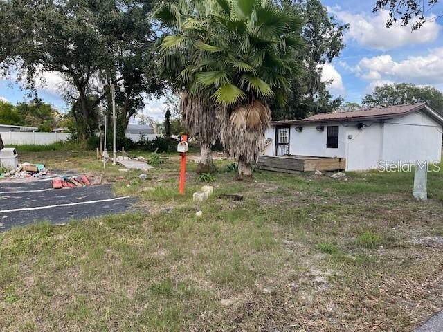 A small, weathered white building stands next to a large palm tree on a grassy lot — 7502 N 40TH STREET, TAMPA, FL