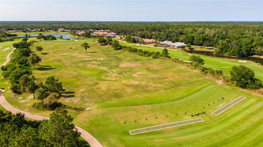 An aerial view shows a golf course driving range with practice mats and surrounding residential homes — 803 LOBLOLLY COURT, PALM COAST, FL