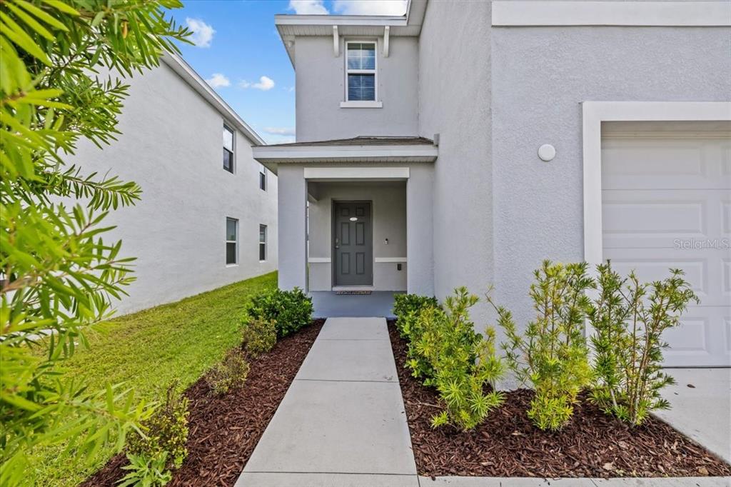 A concrete walkway leads to the front entrance of a two-story gray stucco house — 12148 WHITE CYPRESS PLACE, RIVERVIEW, FL