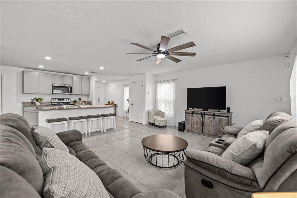 An open-concept living room and kitchen with tile flooring and gray upholstered furniture — 12148 WHITE CYPRESS PLACE, RIVERVIEW, FL