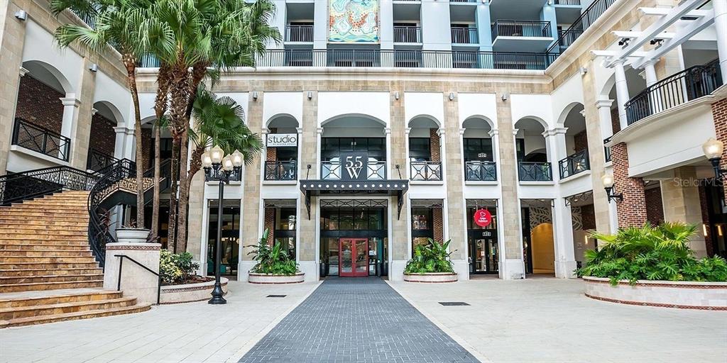 The exterior of a multi-story building features arched entryways, a central staircase, and palm trees — 55-1 W CHURCH STREET, ORLANDO, FL