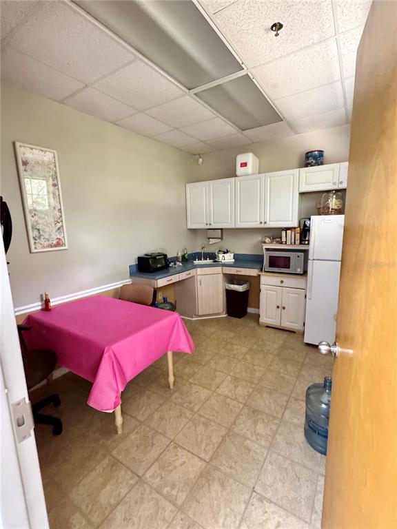 A breakroom features white cabinets, a small kitchenette, a dining table, and tile flooring — 2401 FRIST BOULEVARD UNIT #1-2, FORT PIERCE, FL