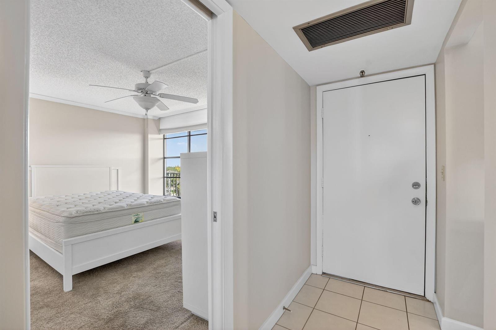 A bedroom with a white bed and ceiling fan is visible through a doorway — 20 Royal Palm Way # 602, Boca Raton FL 33432, BOCA RATON, FL