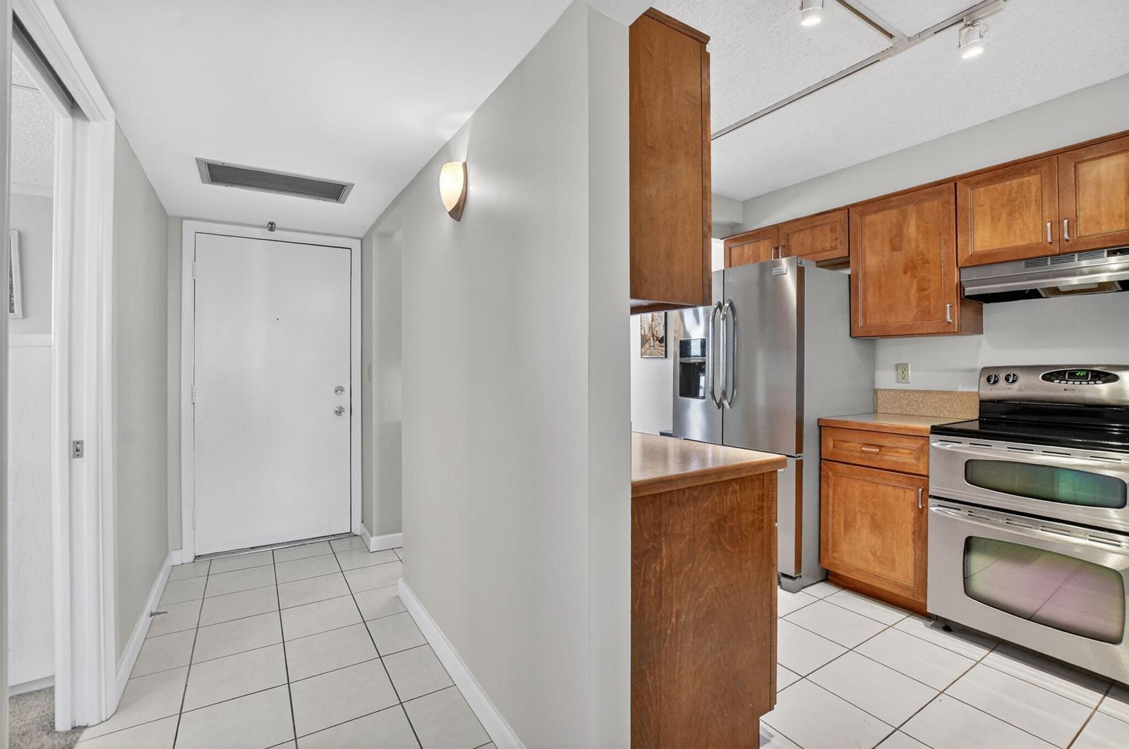 A kitchen with wood cabinets and stainless steel appliances sits beside a tiled entryway — 20 Royal Palm Way # 602, Boca Raton FL 33432, BOCA RATON, FL