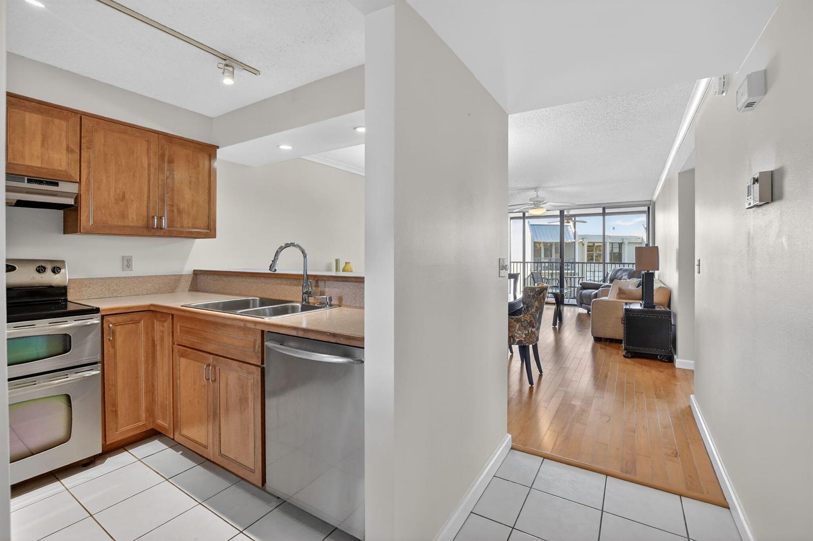 A kitchen with wood cabinets and stainless steel appliances opens into a living area — 20 Royal Palm Way # 602, Boca Raton FL 33432, BOCA RATON, FL