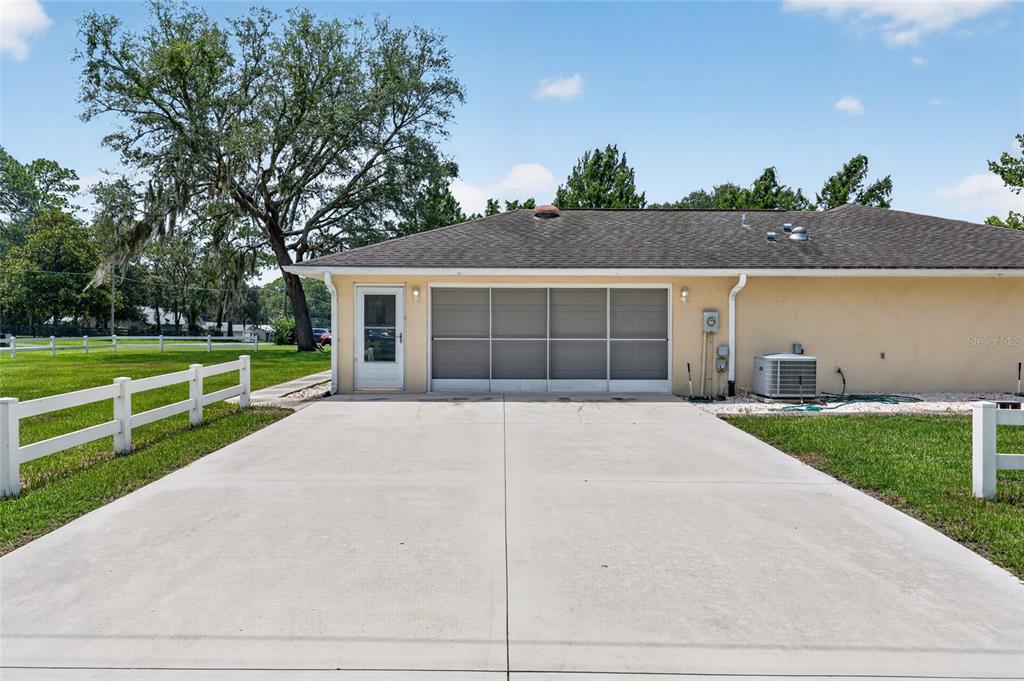 A single-story, tan-colored house with a hip roof sits behind a white rail fence — 16200 SE 91ST COURT, SUMMERFIELD, FL