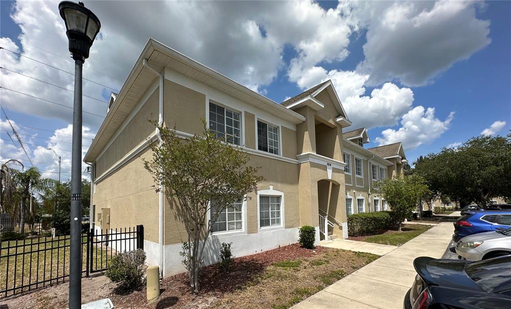 A two-story tan stucco apartment building with a sidewalk and parked cars in front — 9604 SEADALE COURT UNIT 201, RIVERVIEW, FL