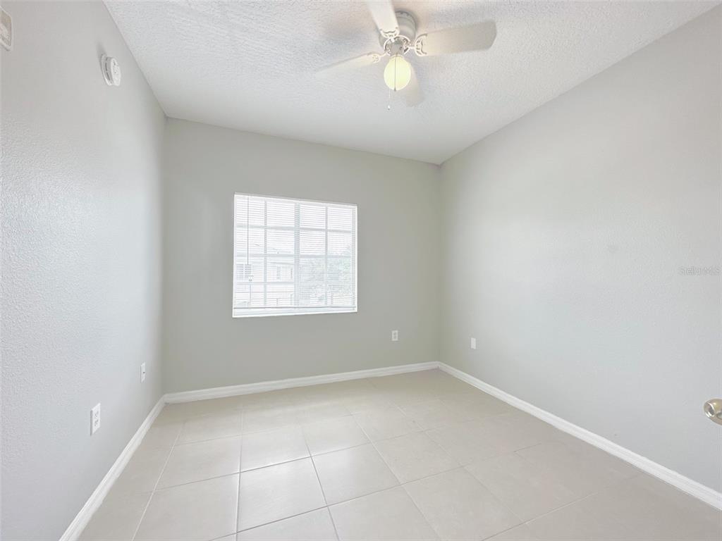 An empty bedroom features light gray walls, a ceiling fan, and light-colored tile flooring — 9604 SEADALE COURT UNIT 201, RIVERVIEW, FL