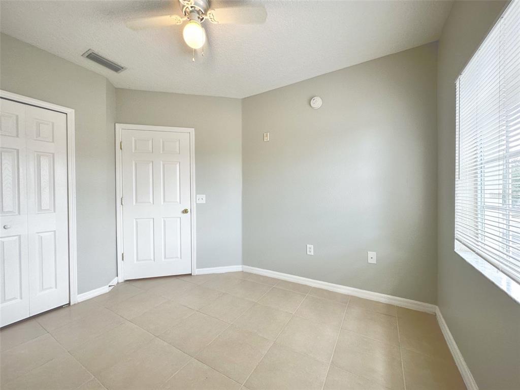 An empty room with light gray walls, tile flooring, a ceiling fan, and two doors — 9604 SEADALE COURT UNIT 201, RIVERVIEW, FL