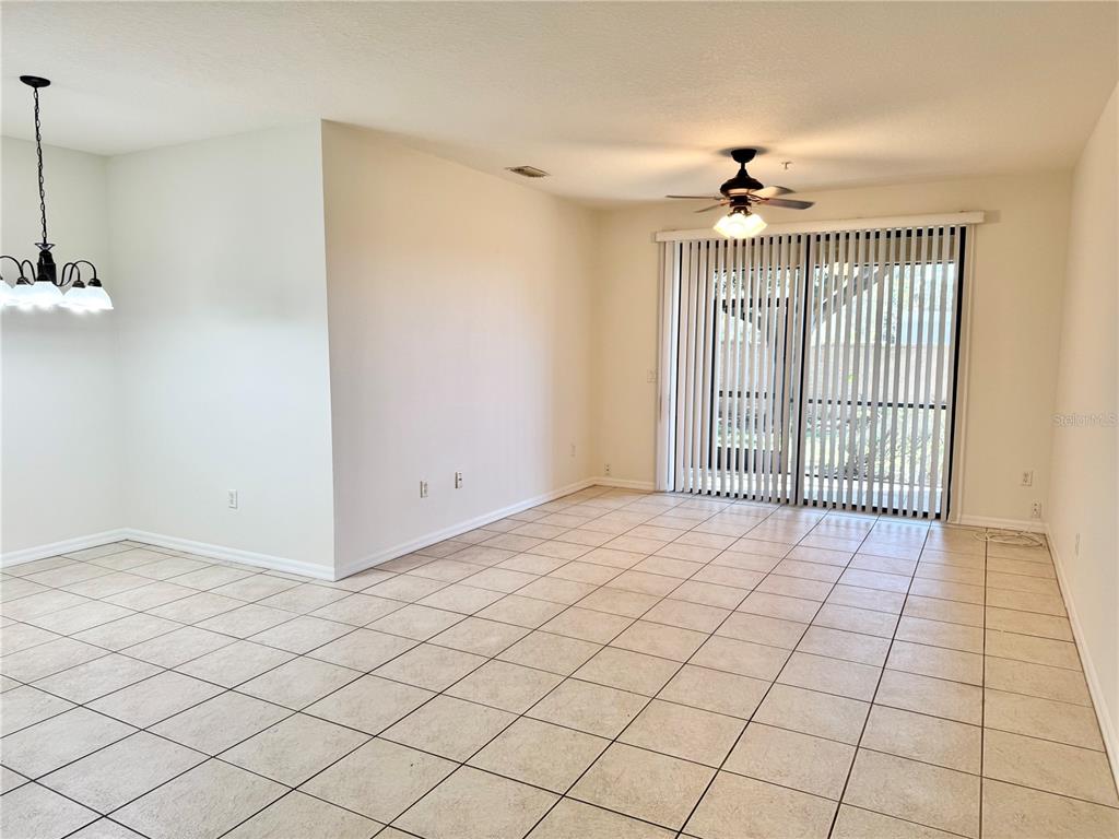 A living room features a white sofa, a round woven coffee table, and a sliding door — 4037 OVERTURE CIRCLE UNIT 4037, BRADENTON, FL