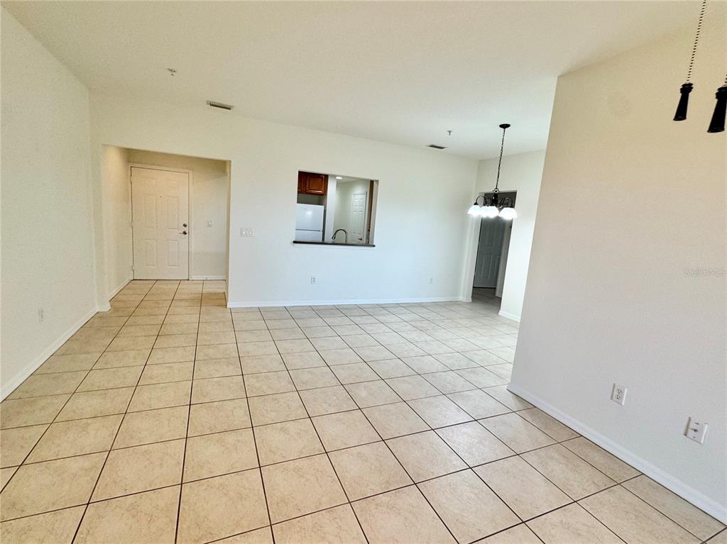 An empty living room features light-colored tile flooring, a ceiling fan, and sliding glass doors — 4037 OVERTURE CIRCLE UNIT 4037, BRADENTON, FL