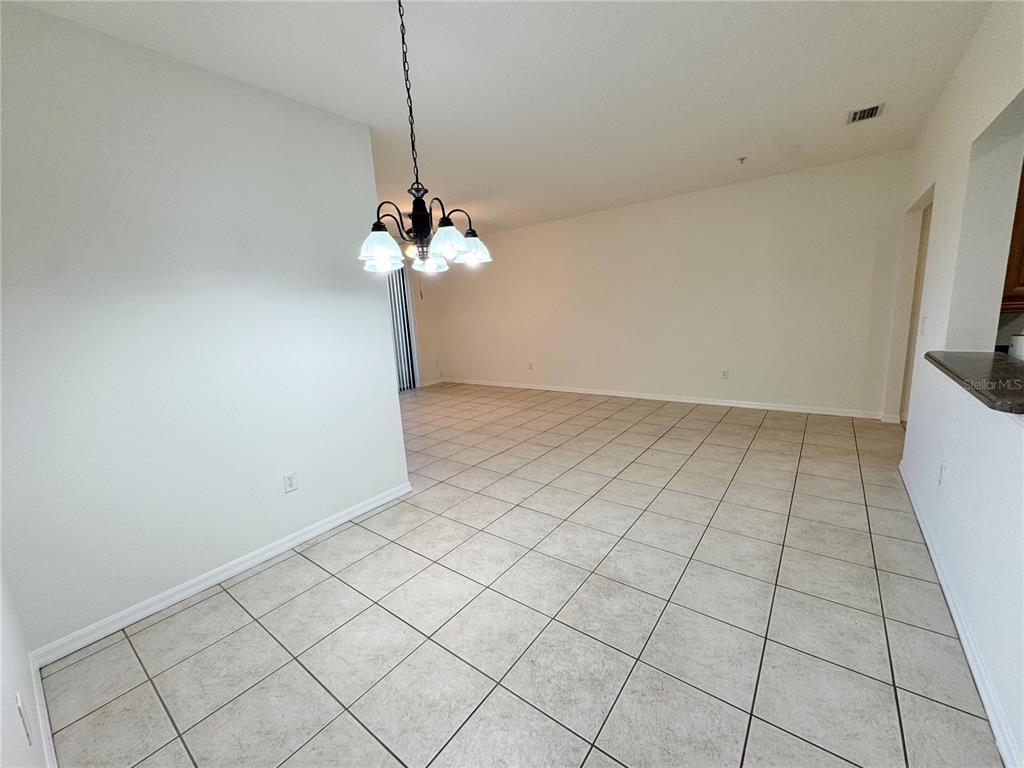 A dining area features a round white table, four rattan chairs, and a tropical painting — 4037 OVERTURE CIRCLE UNIT 4037, BRADENTON, FL