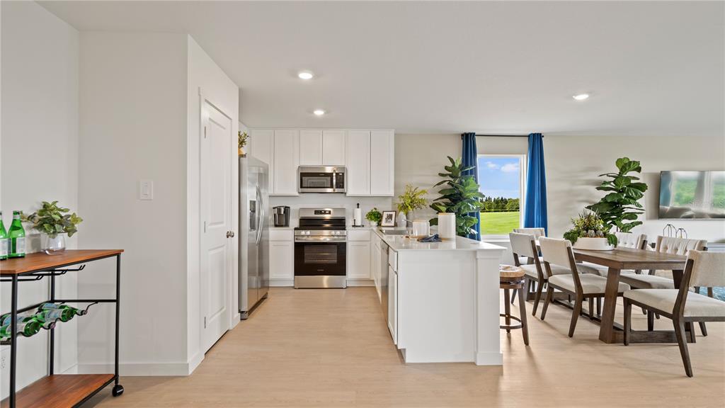 A kitchen with white cabinets, stainless steel appliances, and an island opens to a dining area — 315 NOLA LANE, DUNDEE, FL