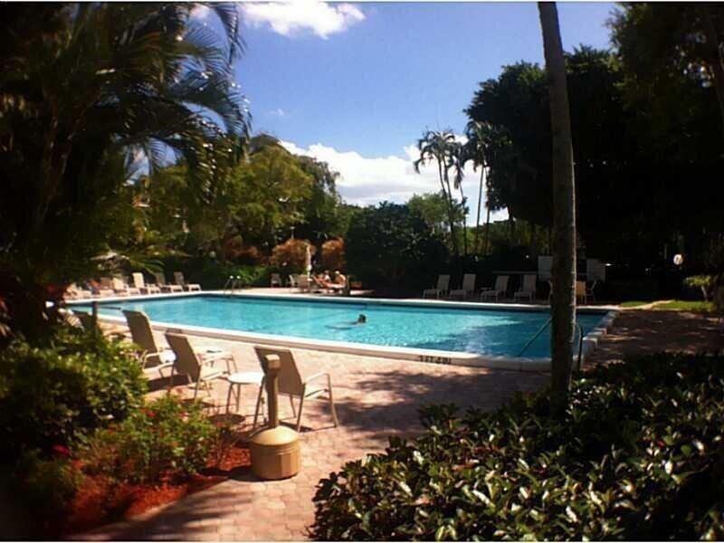 An outdoor swimming pool surrounded by lounge chairs, palm trees, and lush landscaping — 3091 N Course Drive # 303, Pompano Beach FL 33069, POMPANO BEACH, FL