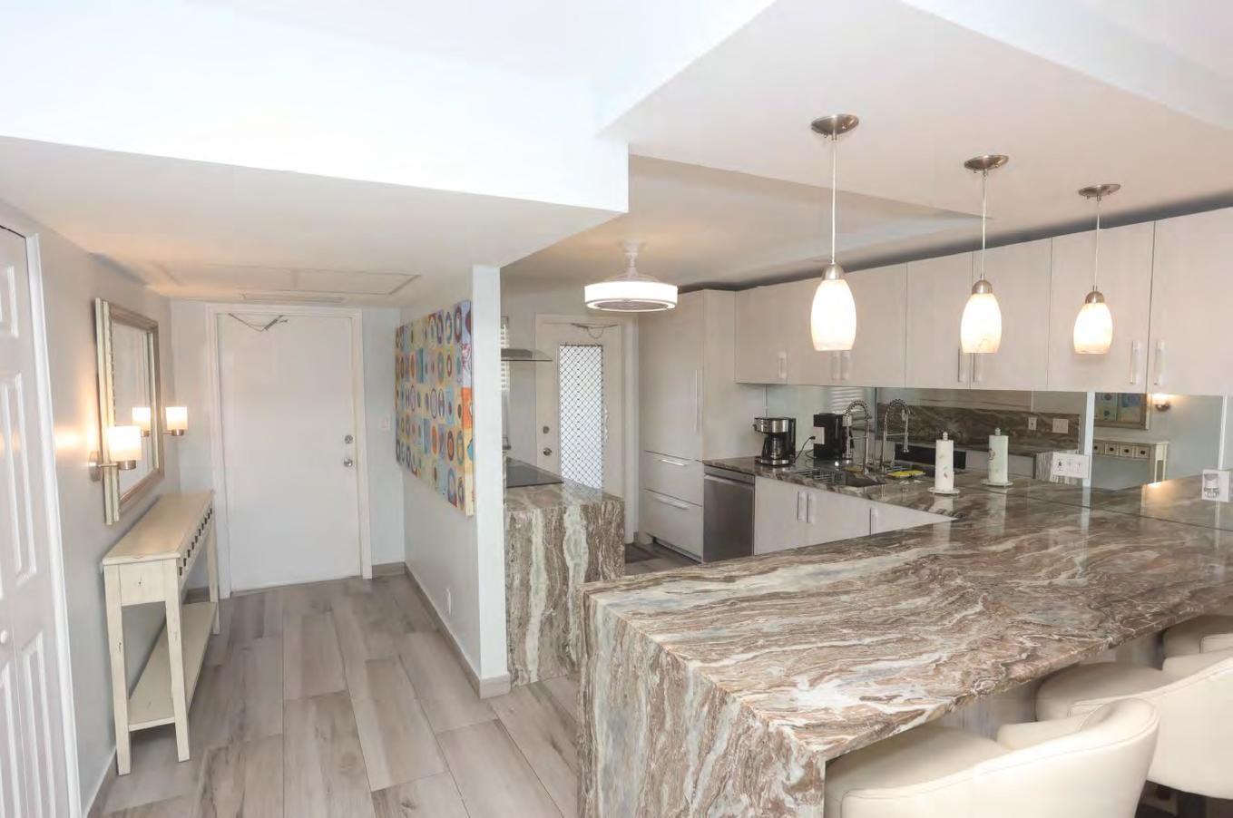 A kitchen with a waterfall marble island, white cabinetry, and pendant lighting over the counter — 3091 N Course Drive # 303, Pompano Beach FL 33069, POMPANO BEACH, FL