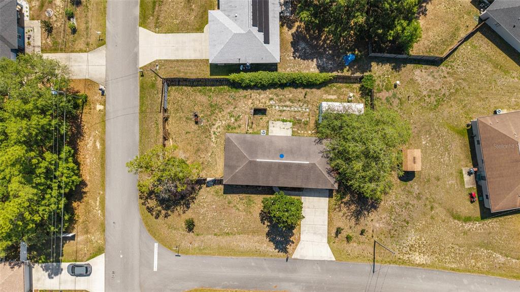 An aerial view shows a single-story house with a driveway situated on a corner lot — 10 PECAN RADIAL TRACE, OCALA, FL