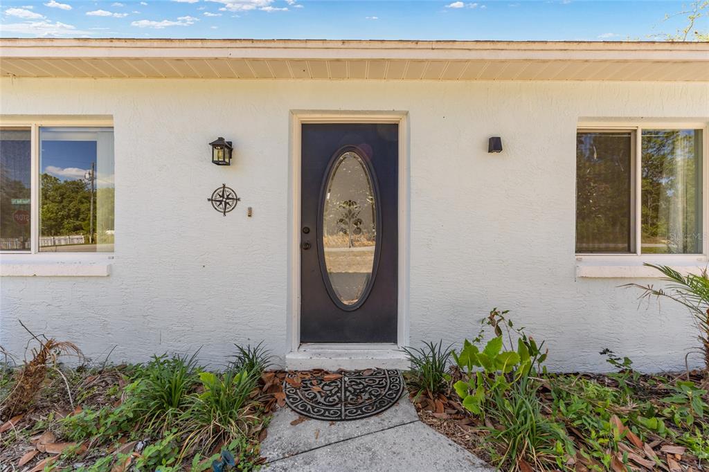 The exterior of a white house features a dark front door with an oval window — 10 PECAN RADIAL TRACE, OCALA, FL