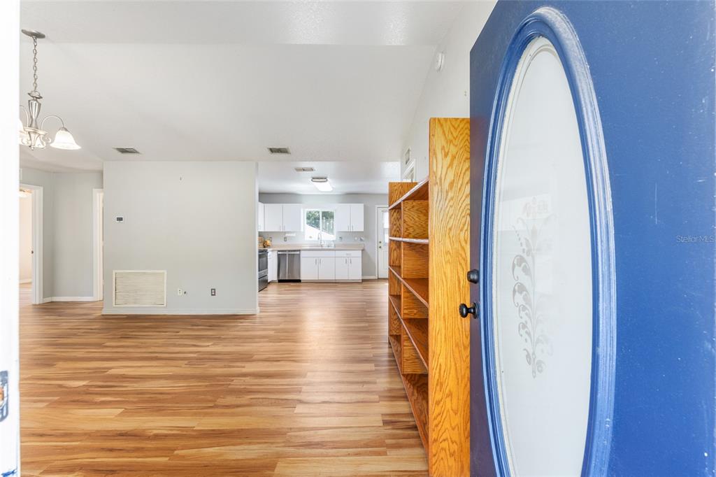 A view from an open blue door into a living area with wood-look flooring — 10 PECAN RADIAL TRACE, OCALA, FL
