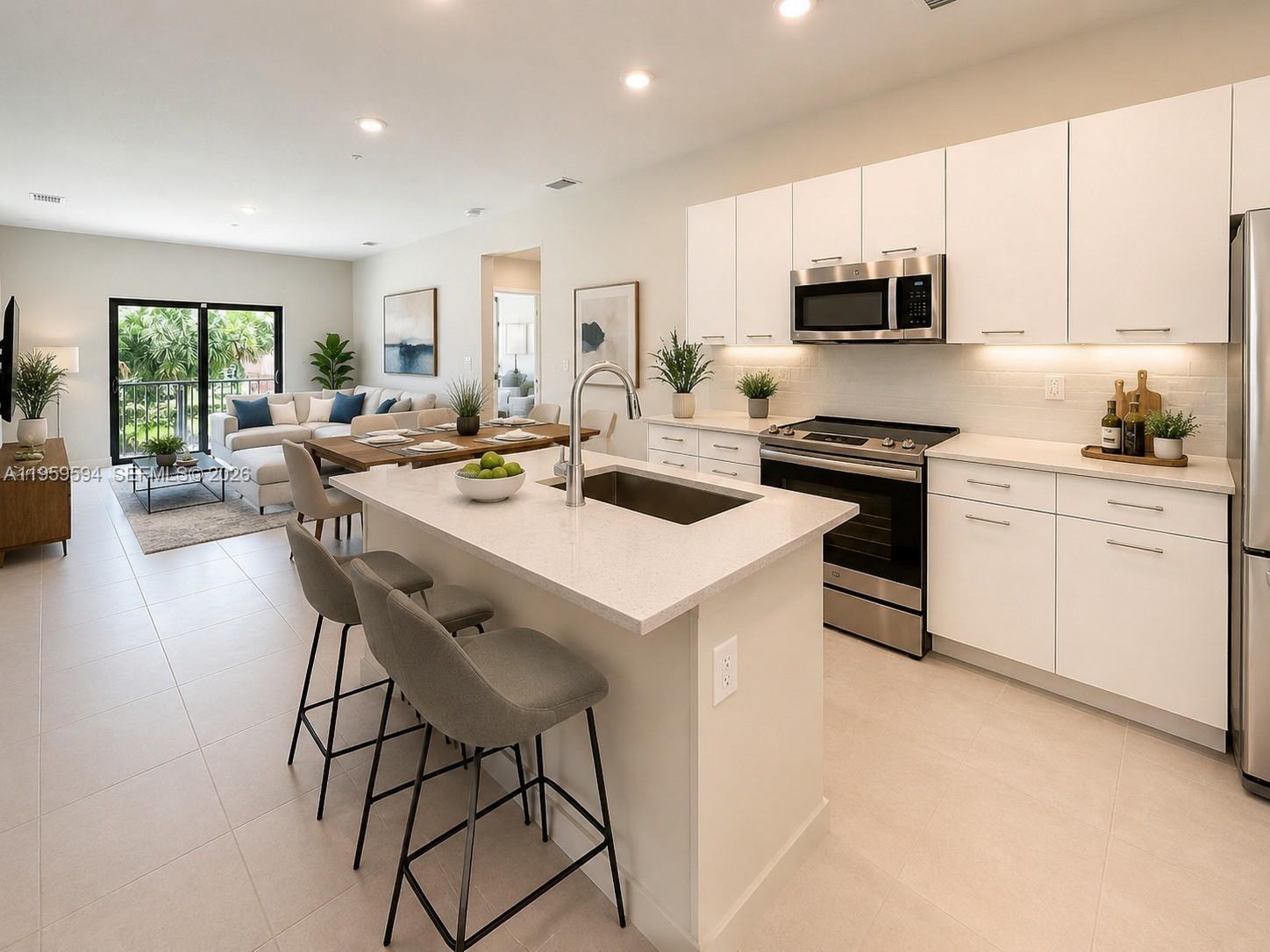 A modern kitchen with white cabinetry and a central island overlooks an open-concept living area — 8001 NW 41st St # 206, Doral FL 33166, DORAL, FL