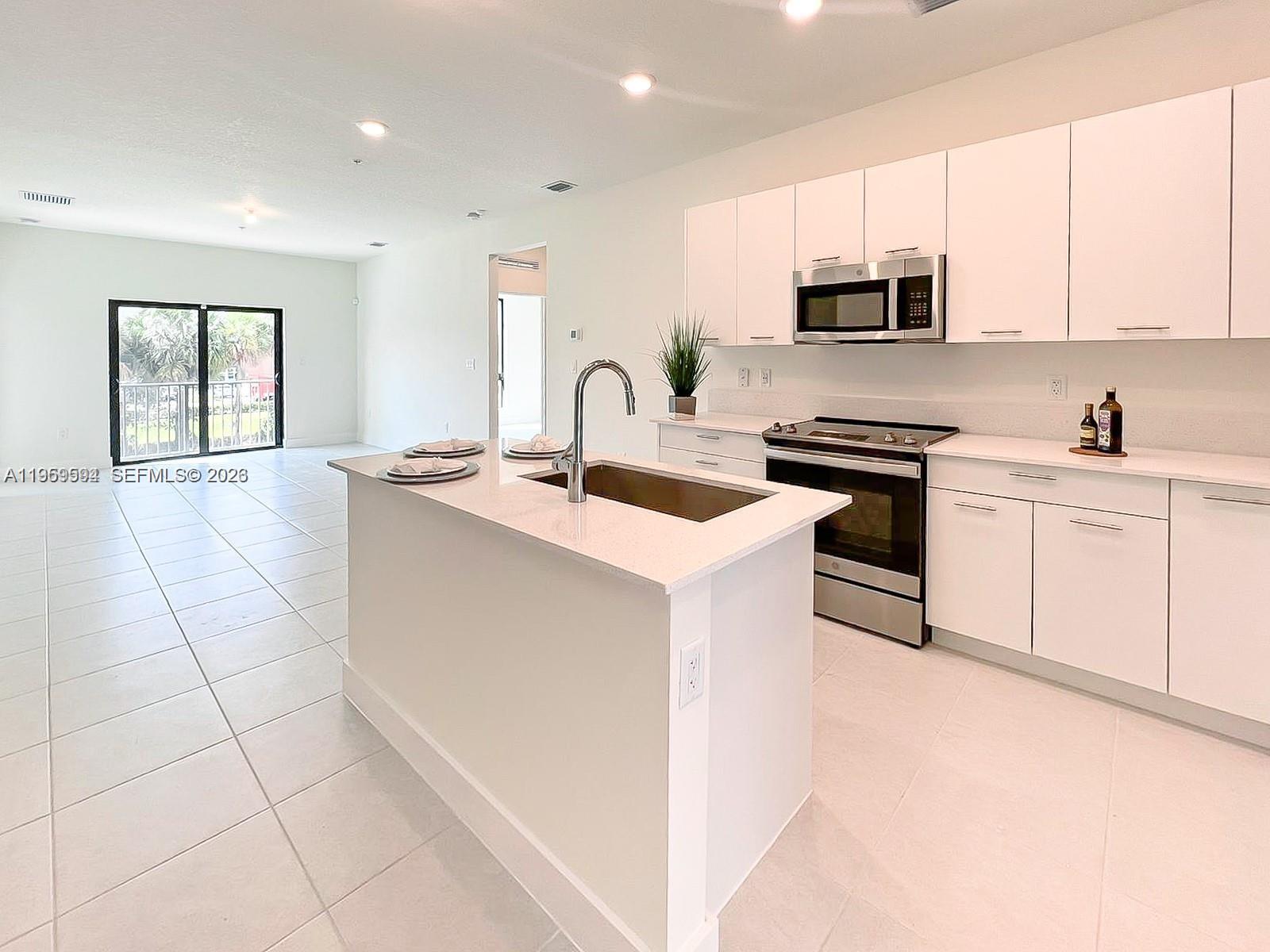 A modern kitchen features white cabinetry, stainless steel appliances, and a central island with seating — 8001 NW 41st St # 206, Doral FL 33166, DORAL, FL