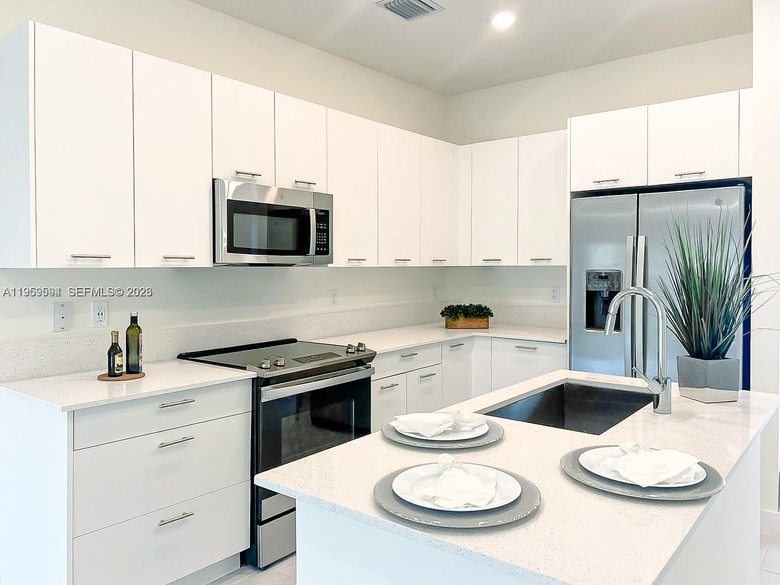 A modern kitchen features white cabinets, stainless steel appliances, and a white quartz island — 8001 NW 41st St # 206, Doral FL 33166, DORAL, FL