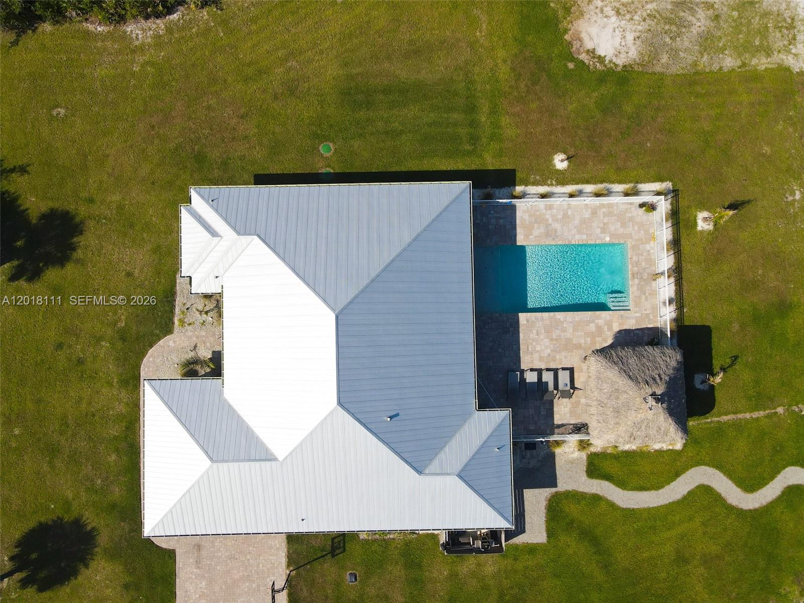 An aerial view shows a house with a metal roof, a pool, and a tiki hut — 5371 S 25th St, Fort Pierce FL 34981, FORT PIERCE, FL