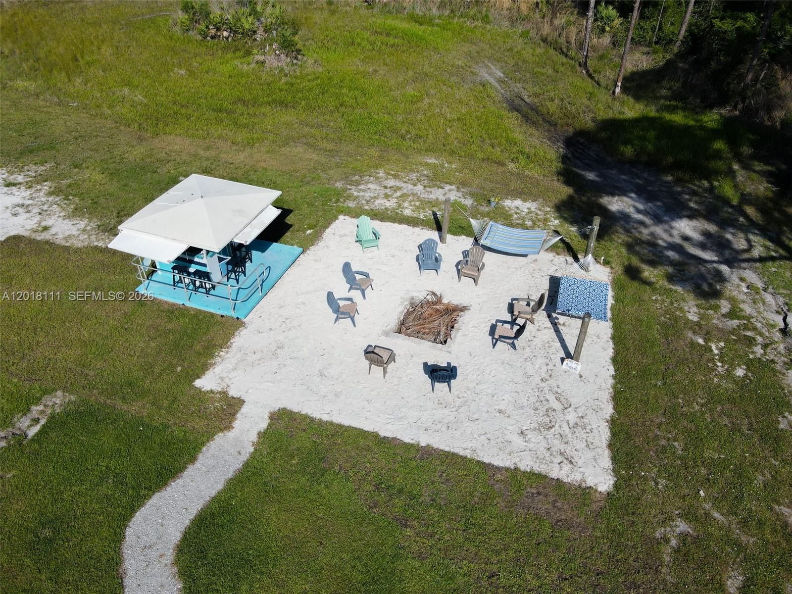 An aerial view shows a sandy fire pit area with chairs, a hammock, and a gazebo — 5371 S 25th St, Fort Pierce FL 34981, FORT PIERCE, FL