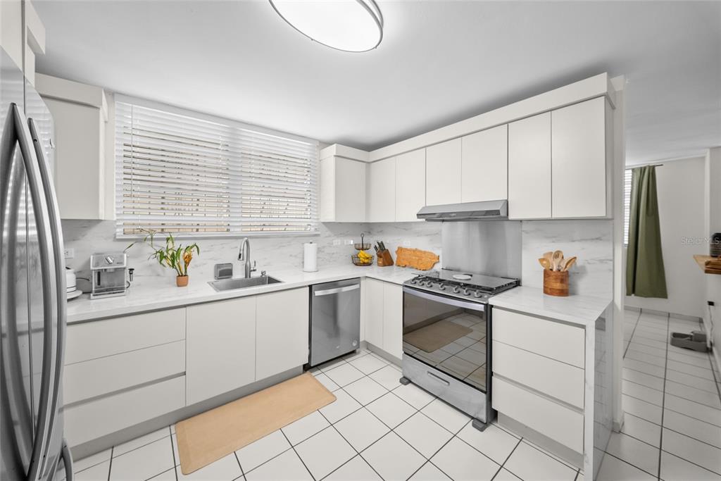 A modern kitchen features white flat-panel cabinets, stainless steel appliances, and white marble-look countertops — N13 CALLE BORIKEN URB. ALTURAS DEL ENCANTO, JUANA DIAZ, PR