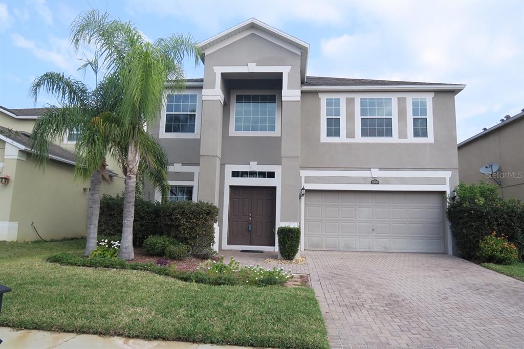 A two-story suburban house features a gray stucco exterior, a palm tree, and a garage — 12029 CITRUSWOOD DRIVE, ORLANDO, FL