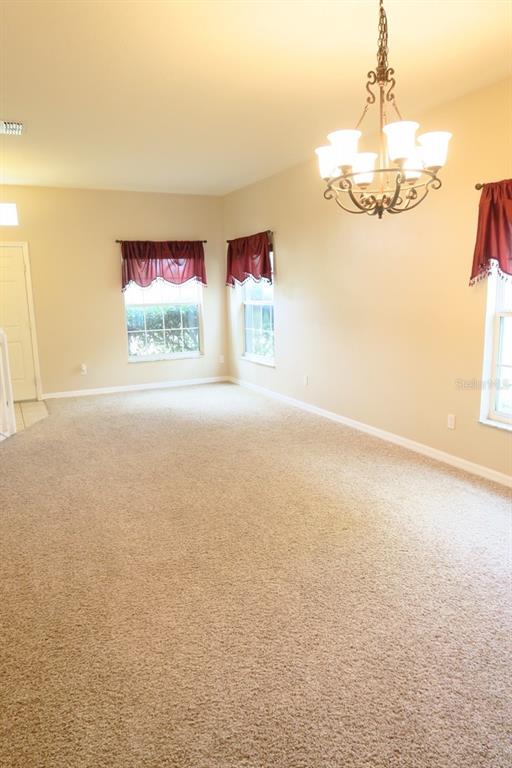 A carpeted dining room features a chandelier, three windows with maroon valances, and beige walls — 12029 CITRUSWOOD DRIVE, ORLANDO, FL