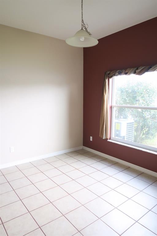 An empty room features beige and maroon walls, tile flooring, and a hanging pendant light — 12029 CITRUSWOOD DRIVE, ORLANDO, FL