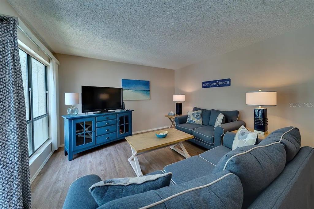 A living room features blue sofas, a wooden coffee table, and a blue media console — 6157 MIDNIGHT PASS ROAD UNIT D32, SARASOTA, FL