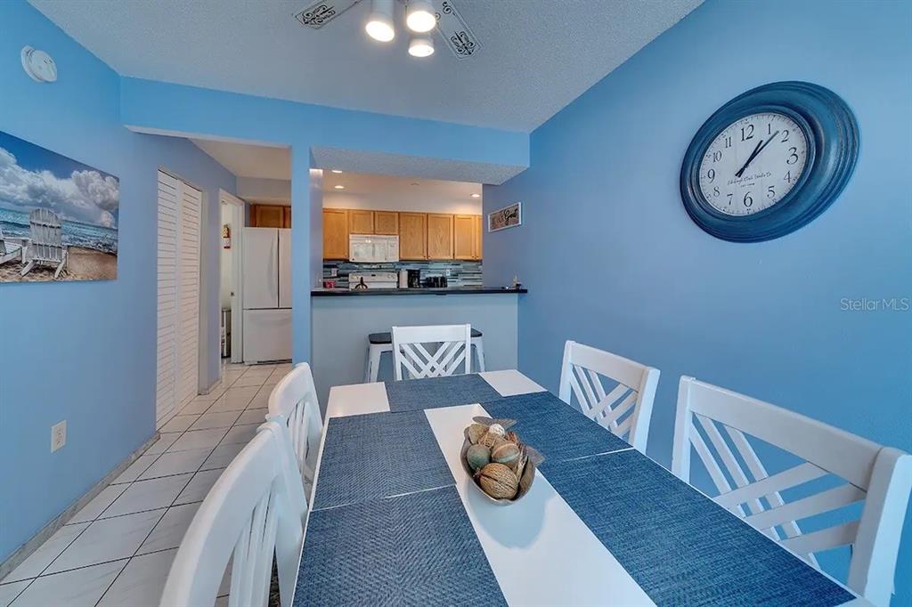 A dining room with a white table, blue runner, and a wall clock on blue walls — 6157 MIDNIGHT PASS ROAD UNIT D32, SARASOTA, FL