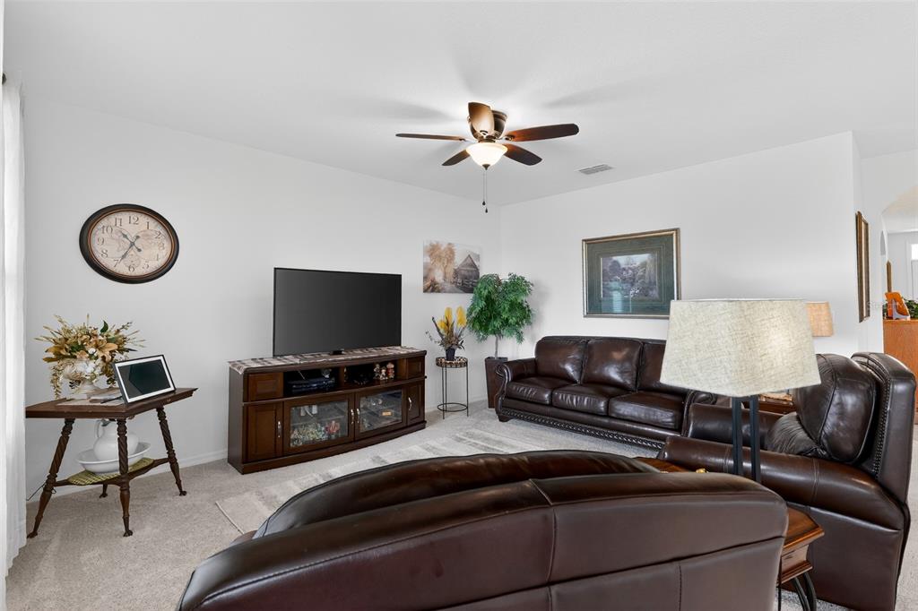 A living room features brown leather furniture, a television on a console, and a ceiling fan — 524 BOARDWALK AVENUE, HAINES CITY, FL