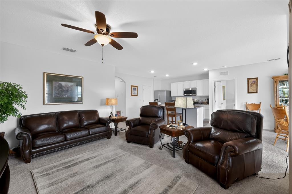 A living room with brown leather furniture, a ceiling fan, and an open kitchen — 524 BOARDWALK AVENUE, HAINES CITY, FL