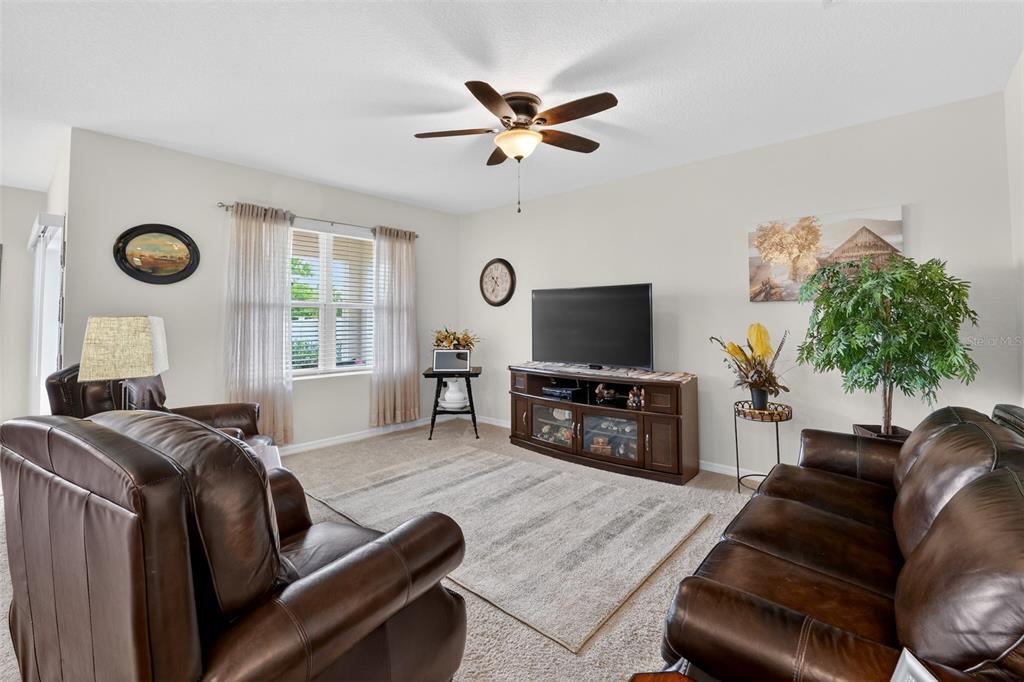 A living room features brown leather furniture, a television on a console, and a ceiling fan — 524 BOARDWALK AVENUE, HAINES CITY, FL