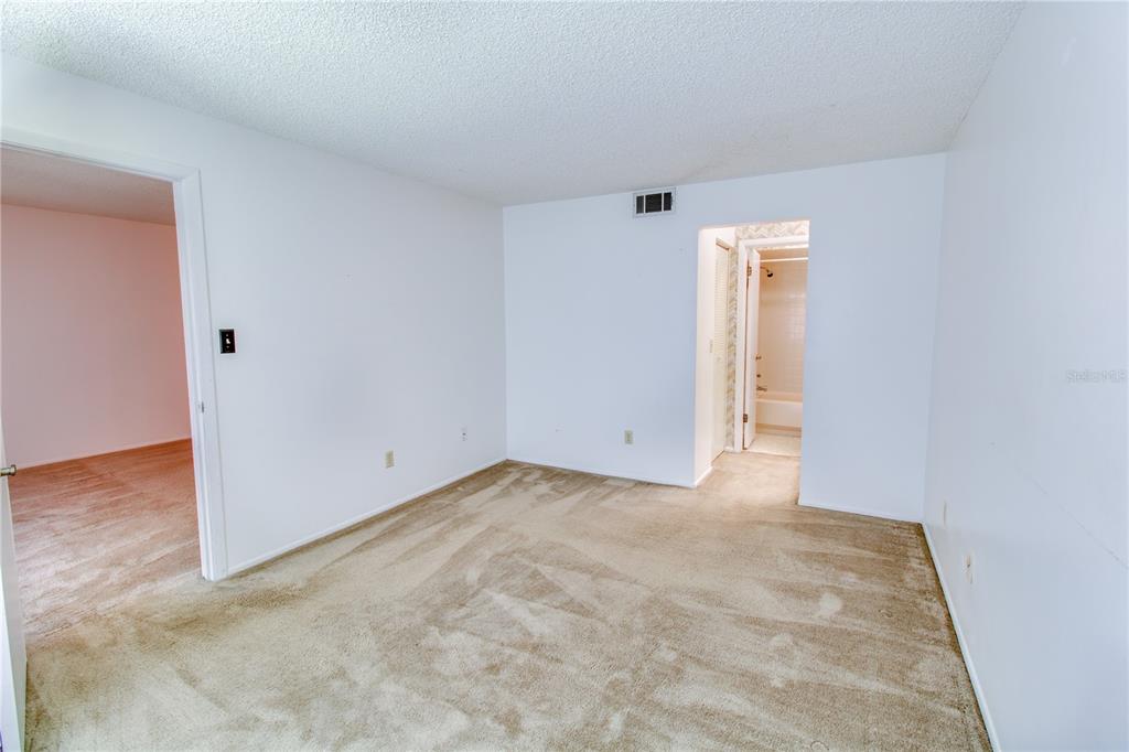 An empty bedroom with beige carpet, white walls, and doorways leading to other rooms — 3293 WESTRIDGE BOULEVARD UNIT 203, ORLANDO, FL