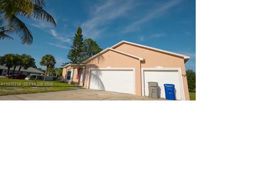 A peach-colored house features a two-car garage and a driveway under a blue sky — 8720 97th Ave, Vero Beach FL 32967, VERO BEACH, FL