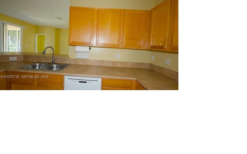 A kitchen features light wood cabinets, tan laminate countertops, and a stainless steel sink — 8720 97th Ave, Vero Beach FL 32967, VERO BEACH, FL
