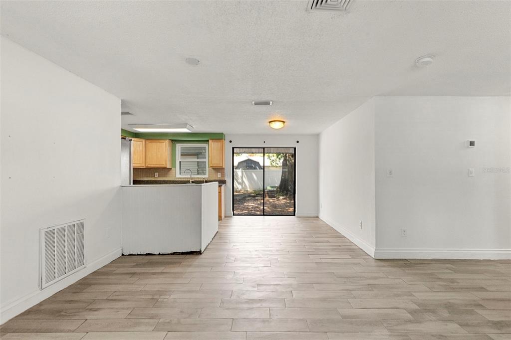 An open-concept living area features light wood-look tile flooring and a kitchen with wood cabinets — 5557 146TH TERRACE N, CLEARWATER, FL