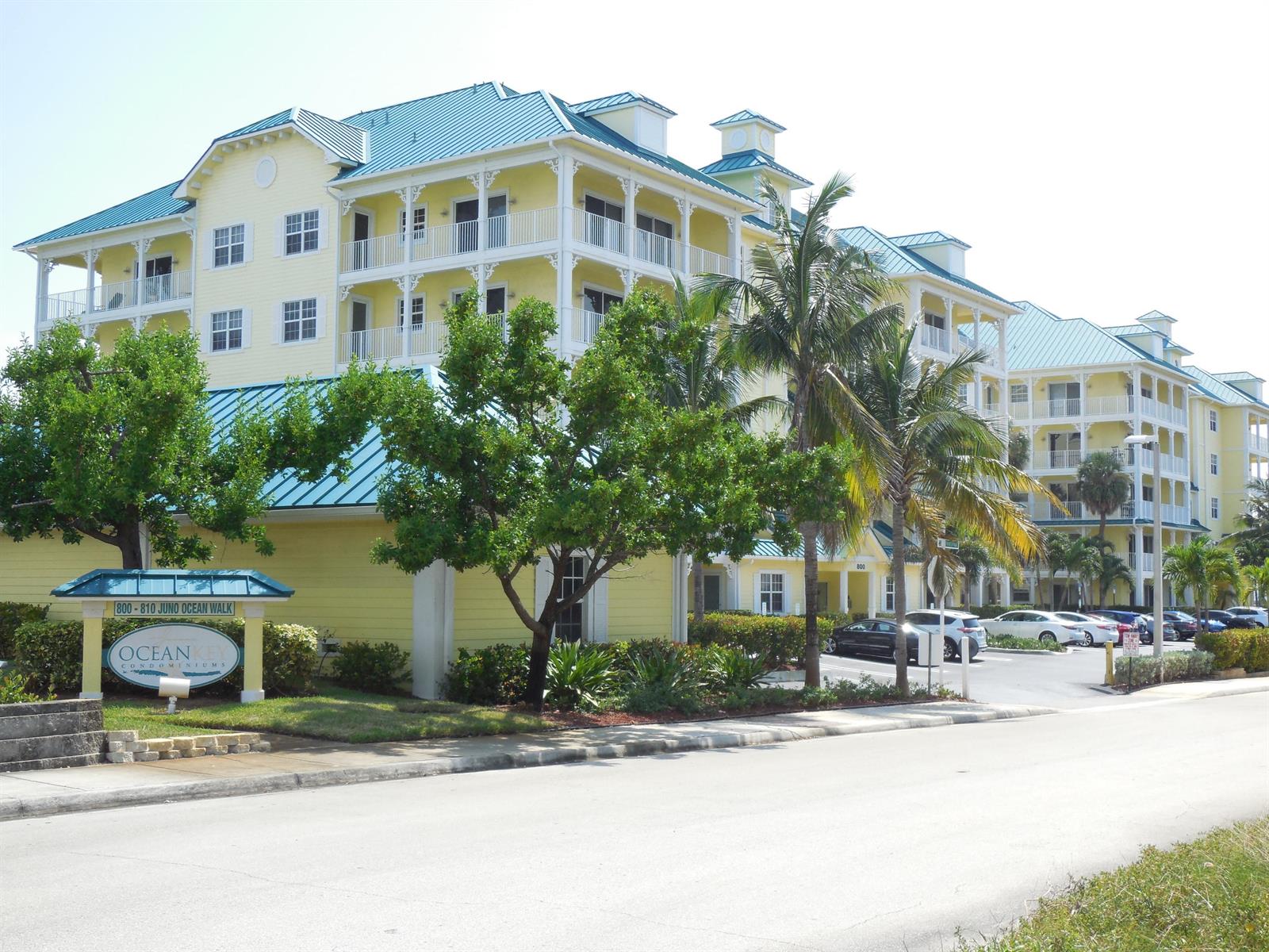 A yellow multi-story condominium building with a teal metal roof and palm trees — 800 Juno Ocean Walk # 301a, Juno Beach FL 33408, JUNO BEACH, FL